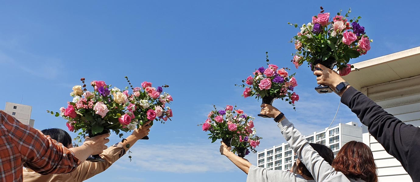 사람들이 플라워 체험을 한 후 결과물을 하늘위로 들어올려 찍은 사진