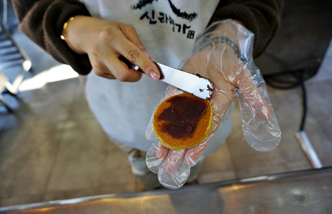 찰보리빵에 팥소를 얇기 바르는 모습