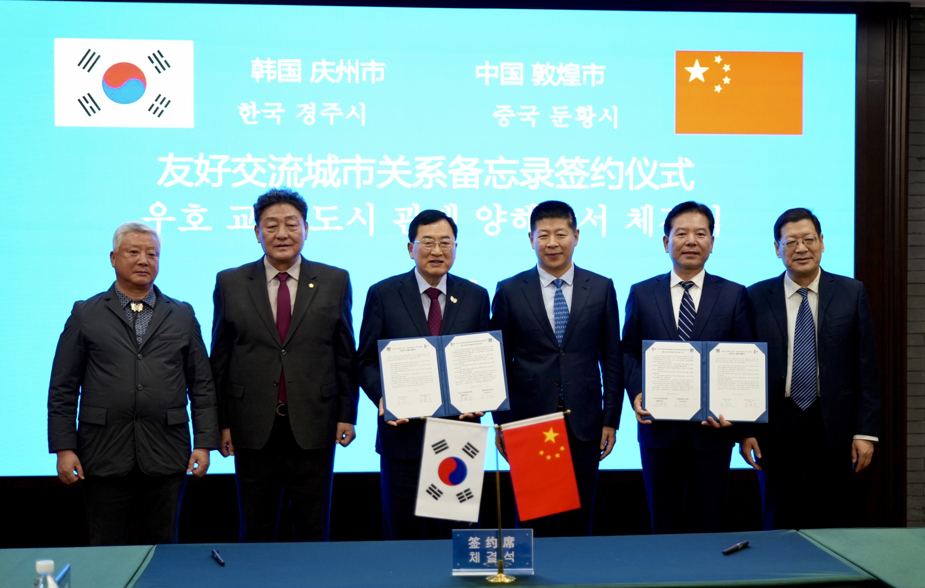 주낙영 경주시장과 주젠쥔 둔황시장이 18일 둔황시청에서 경주시–둔황시 우호도시 협정서를 교환한 뒤 기념촬영을 하고 있다. 좌측 세 번째부터 주낙영 경주시장, 왕엔췬 둔황시 당서기, 주젠쥔 둔황시장