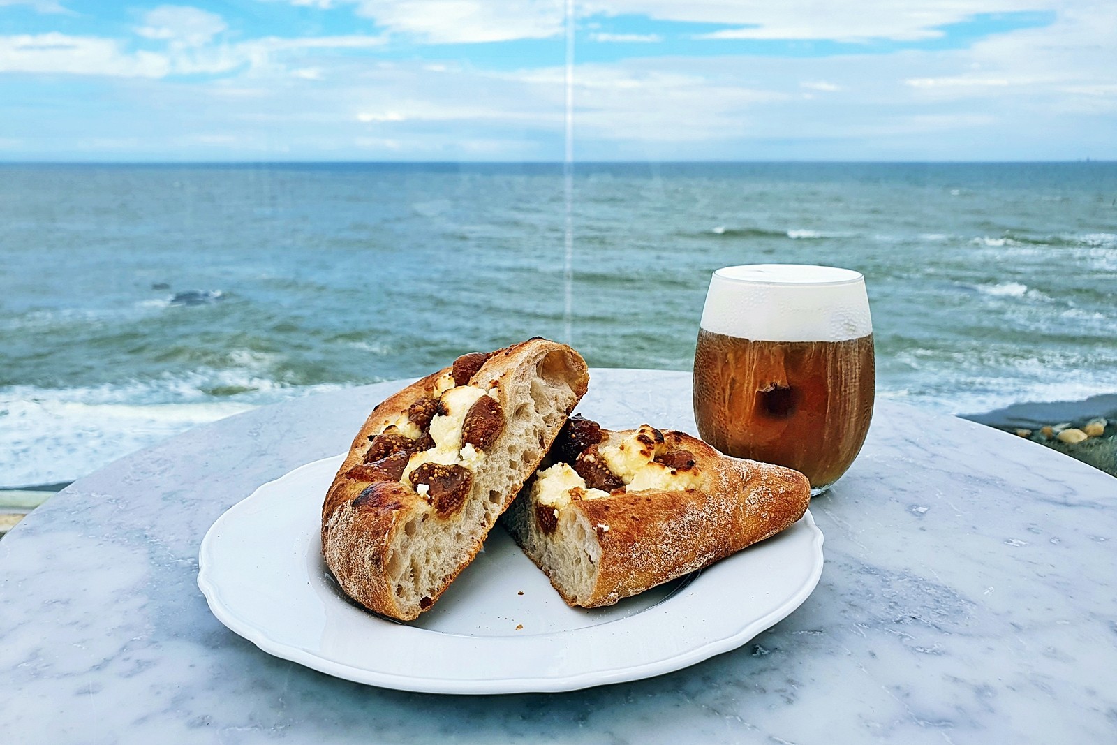바다전망이 보이는 테이블 위에 올려진 빵과 음료